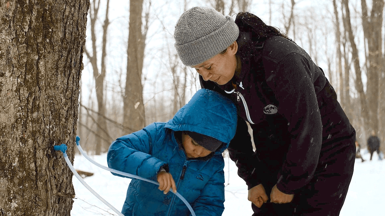 A woman and child looking at something in the snow.